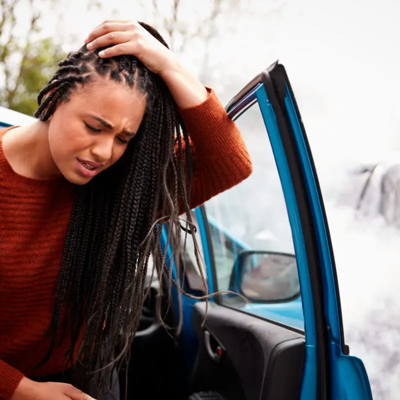 female driver getting out of her car with a car accident concussion