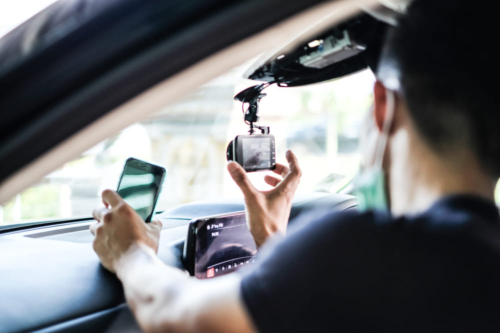 uber driver adjusting dashcam in vehicle