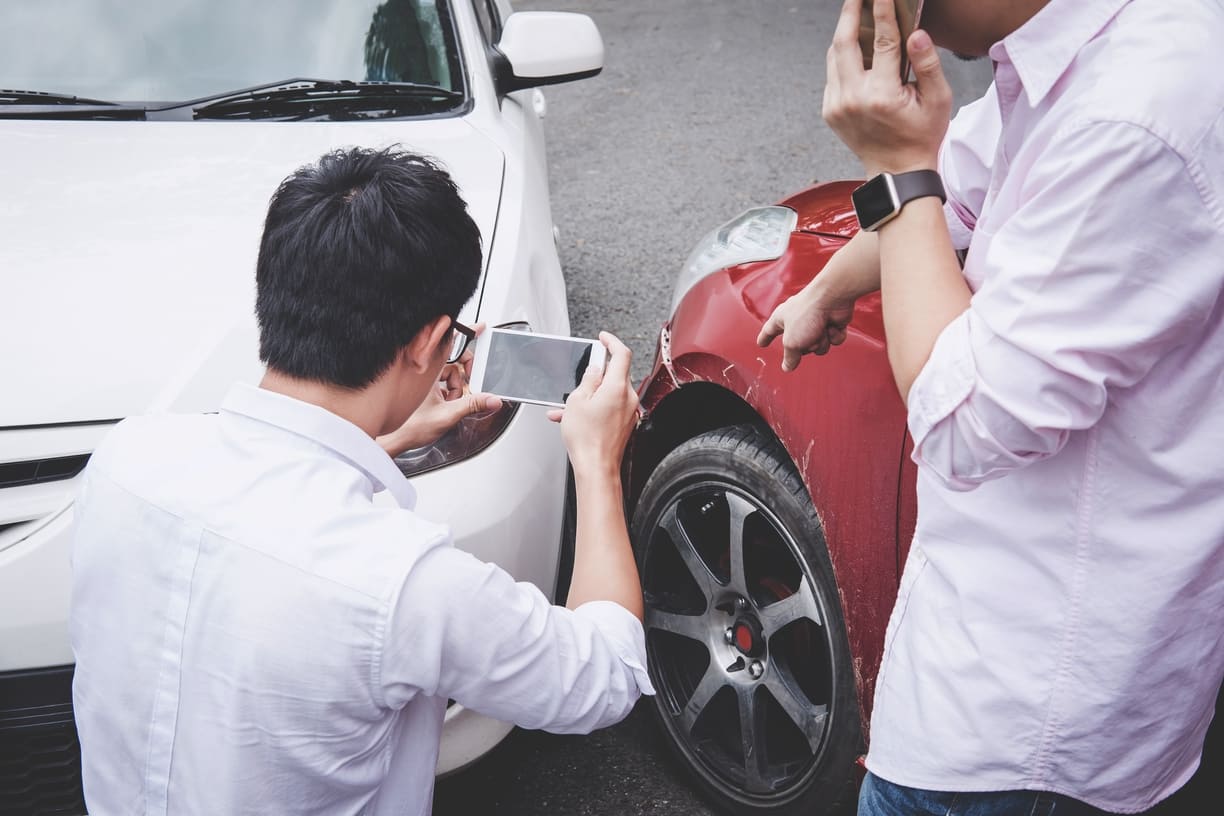 driver taking pictures on phone at scene of car accident
